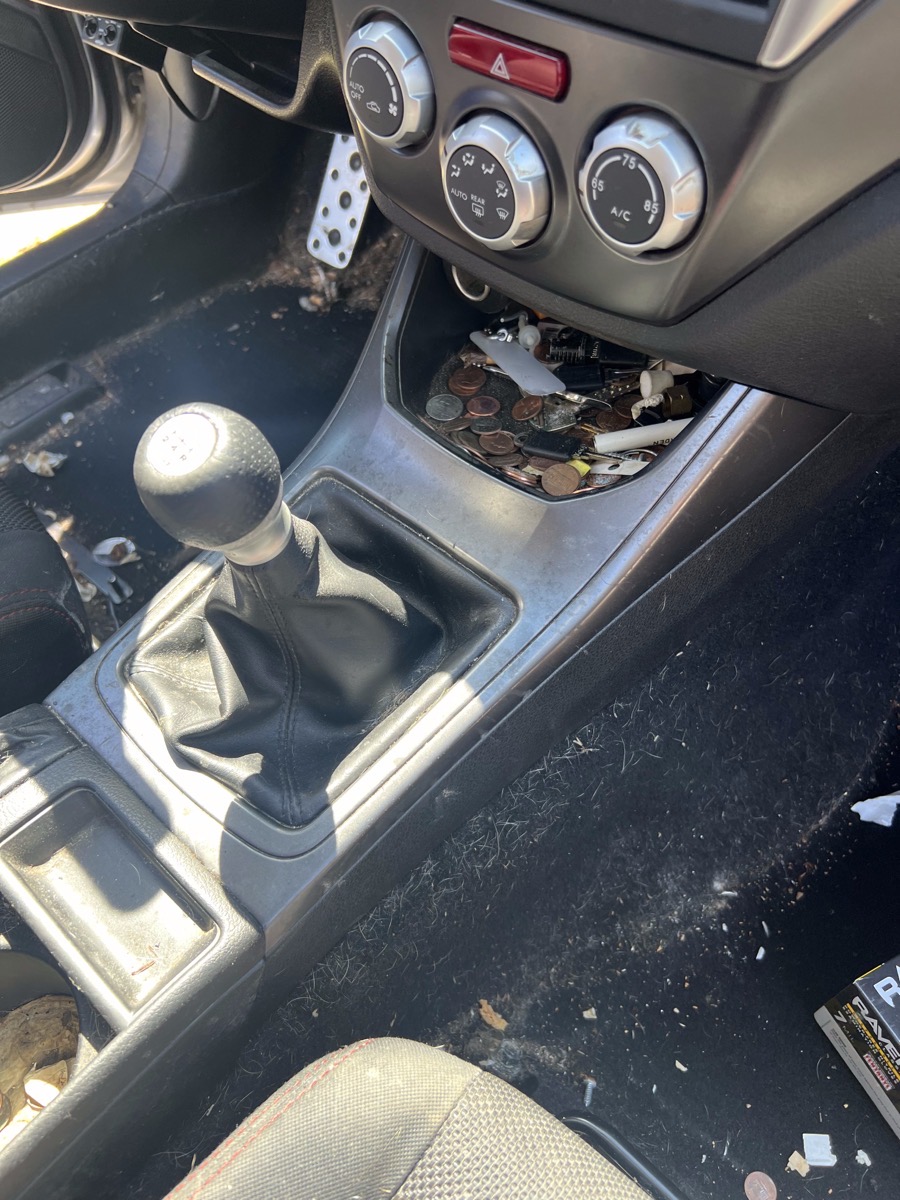 Cluttered car center console before an interior detail